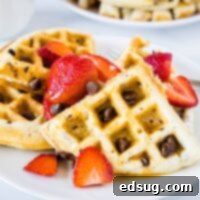 Decadent Chocolate Chip Waffles 9 A stack of chocolate chip waffles with syrup and berries.