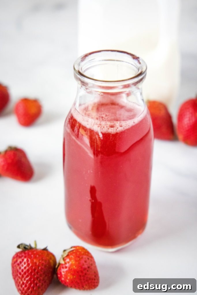 A glass jar filled with rich, red homemade strawberry syrup, ready for use