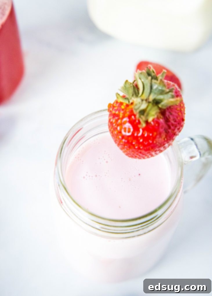 Looking down on a full cup of refreshing homemade strawberry milk, garnished with a strawberry, ready to be enjoyed.