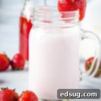 close up of strawberry milk with strawberry on rim of glass