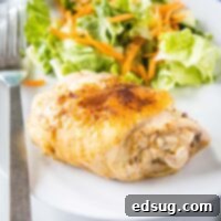 close up of cooked chicken thigh on a plate with salad