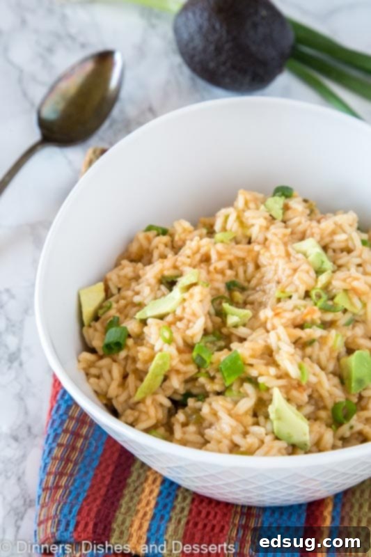A serving of Mexican rice with avocado on a plate, garnished with fresh cilantro.