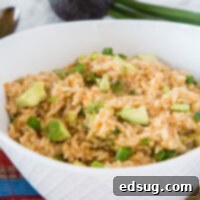 A tantalizing bowl of fluffy Mexican rice, with avocado chunks and green onions visible.