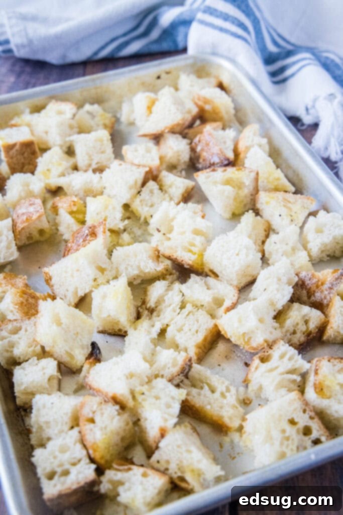 Crispy Homemade Croutons 6 Bread cubes evenly tossed with olive oil, salt, and pepper on a baking tray, ready to bake