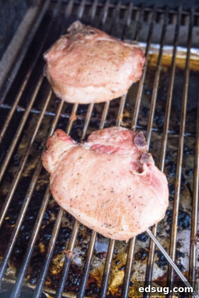 Succulent Smoked Pork Chops 5 Perfectly cooked smoked pork chops being removed from the grill grates.