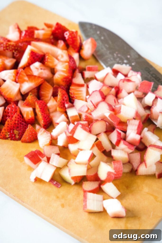Delightful Strawberry Rhubarb Muffins 3 chopped strawberries and rhubarb on a cutting board, ready for baking
