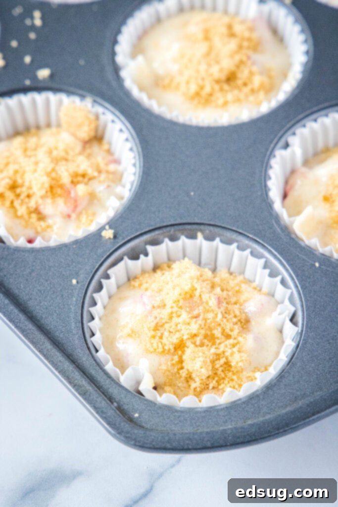 Delightful Strawberry Rhubarb Muffins 4 muffin batter in a tin with brown sugar and cinnamon sprinkled on top