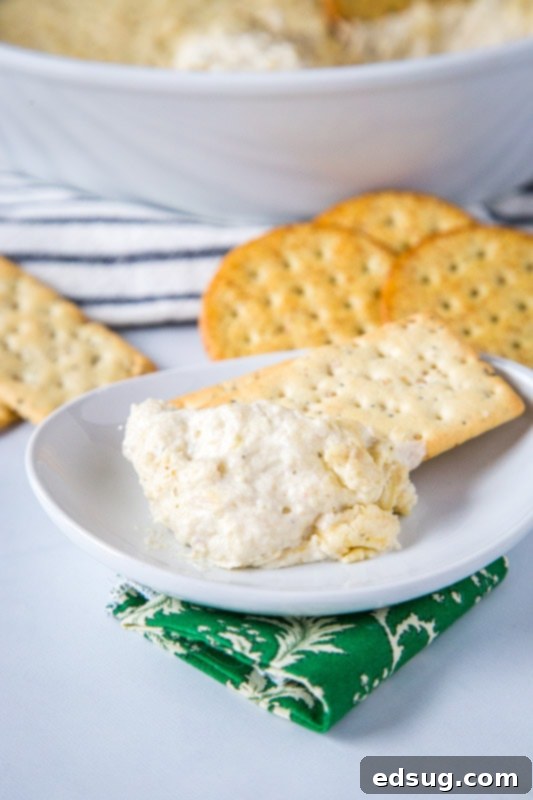 A bubbling hot, cheesy baked artichoke dip in a white baking dish, ready to be served as an appetizer.