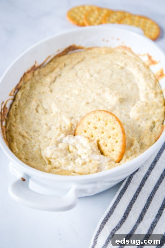Close-up of the creamy, unbaked hot artichoke dip mixture in a food processor, showcasing its smooth texture.