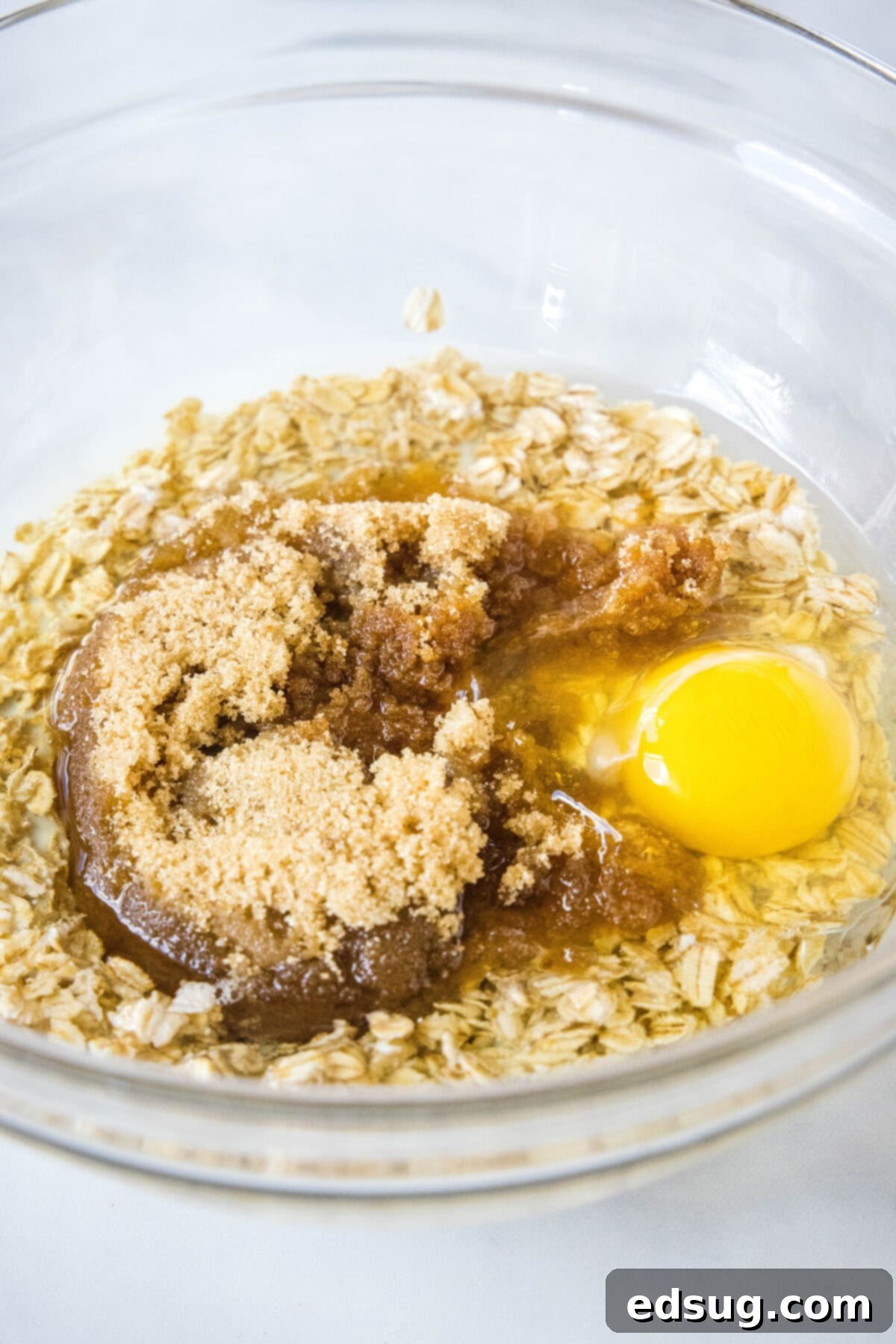 Eggs and wet ingredients combined with brown sugar in a glass bowl.