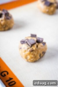 Copycat Chick-fil-A Chocolate Chunk Cookie Recipe 8 A perfectly portioned ball of Chick-fil-A cookie dough on a baking sheet, topped with extra chocolate chunks, ready for the oven.