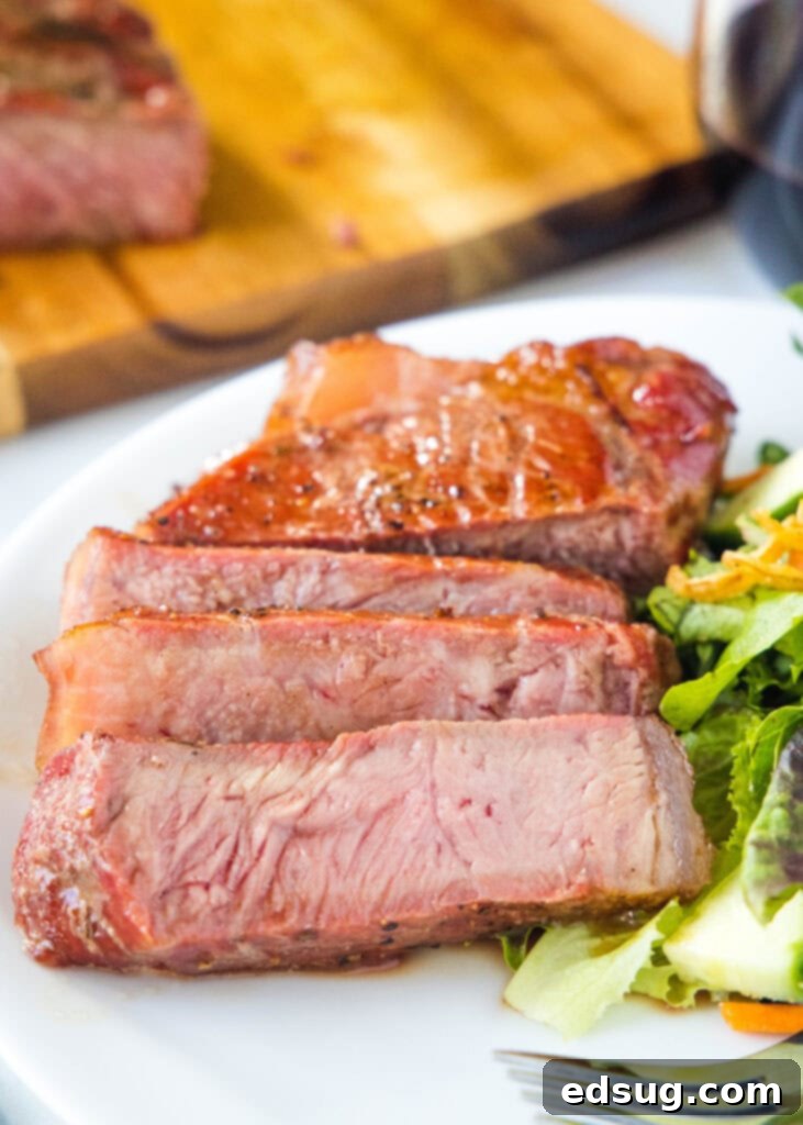 sliced smoked steak on a plate with salad and a fork