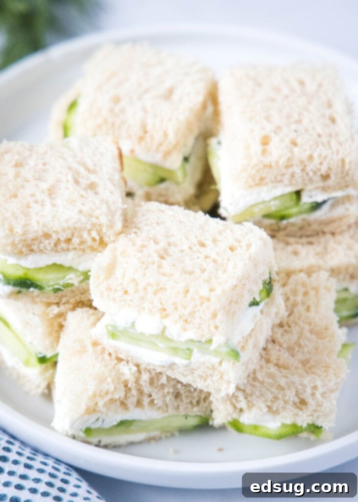 Cucumber Sandwiches 5 A close-up view looking down on a plate filled with freshly cut cucumber sandwiches, arranged beautifully.
