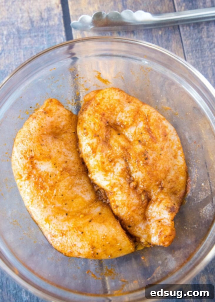 Bowl of raw chicken breast pieces coated in a savory spice blend, ready for the air fryer