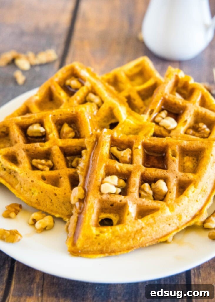 Spiced Pumpkin Waffles 4 Close-up of a stack of pumpkin waffle pieces on a white plate, ready to be served.