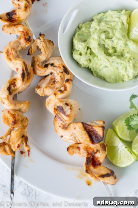 Zesty Chicken Kebabs 3 grilled chicken on skewers with avocado dipping sauce on a plate