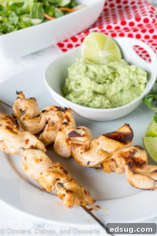 Zesty Chicken Kebabs 4 grilled chicken on skewers with avocado dipping sauce on a plate