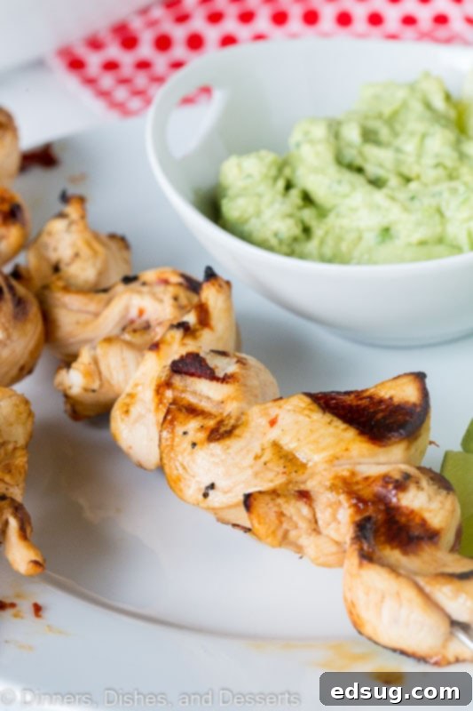 Zesty Chicken Kebabs 5 grilled chicken on skewers with avocado dipping sauce on a plate