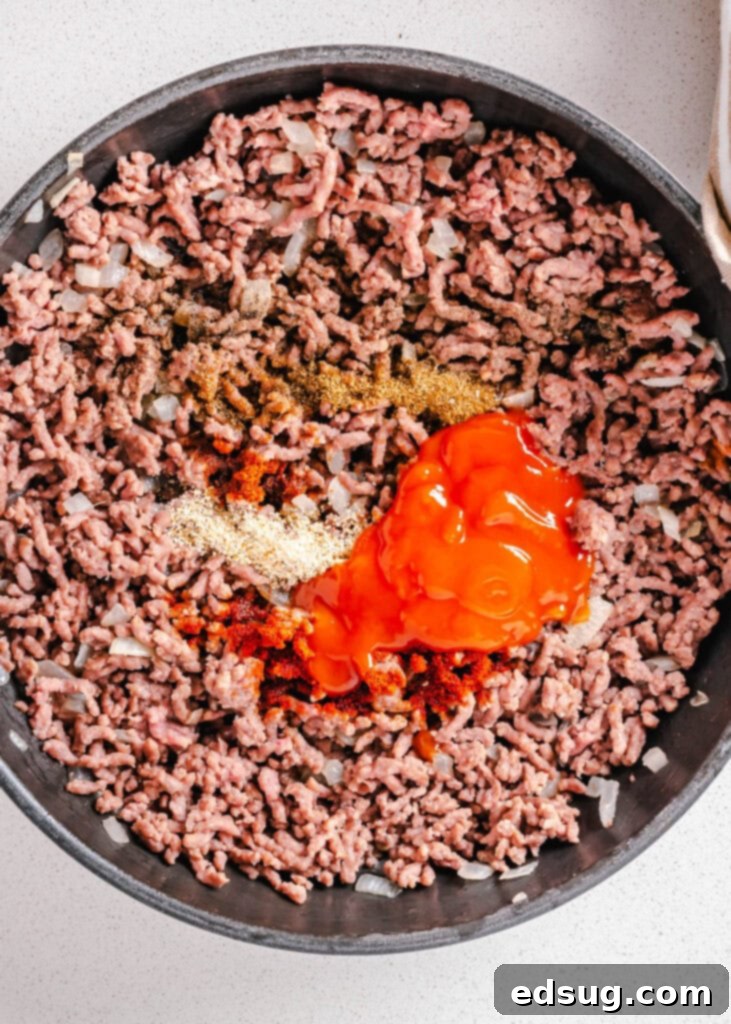 Zesty Beef Lettuce Wraps 3 Close-up of seasoned ground beef simmering in a skillet with tomato sauce and aromatic spices, creating a rich and savory filling.