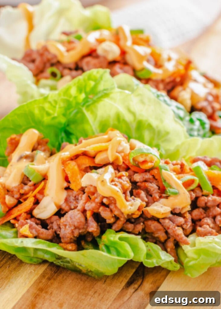 Zesty Beef Lettuce Wraps 4 Freshly prepared ground beef lettuce wraps neatly arranged on a rustic wooden cutting board, highlighting their simple elegance and healthy appeal.