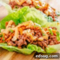Zesty Beef Lettuce Wraps 7 Close up of a savory beef lettuce wrap on a wooden board, highlighting the fresh ingredients and rich filling.