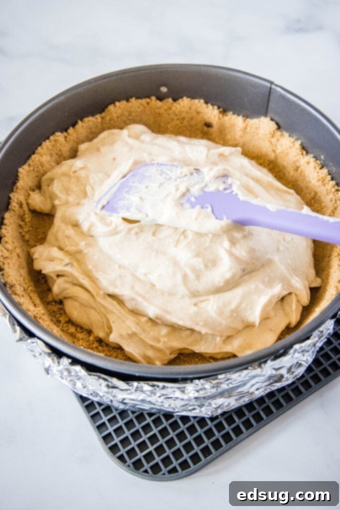 Creamy cheesecake filling poured into a golden graham cracker crust, ready for baking.