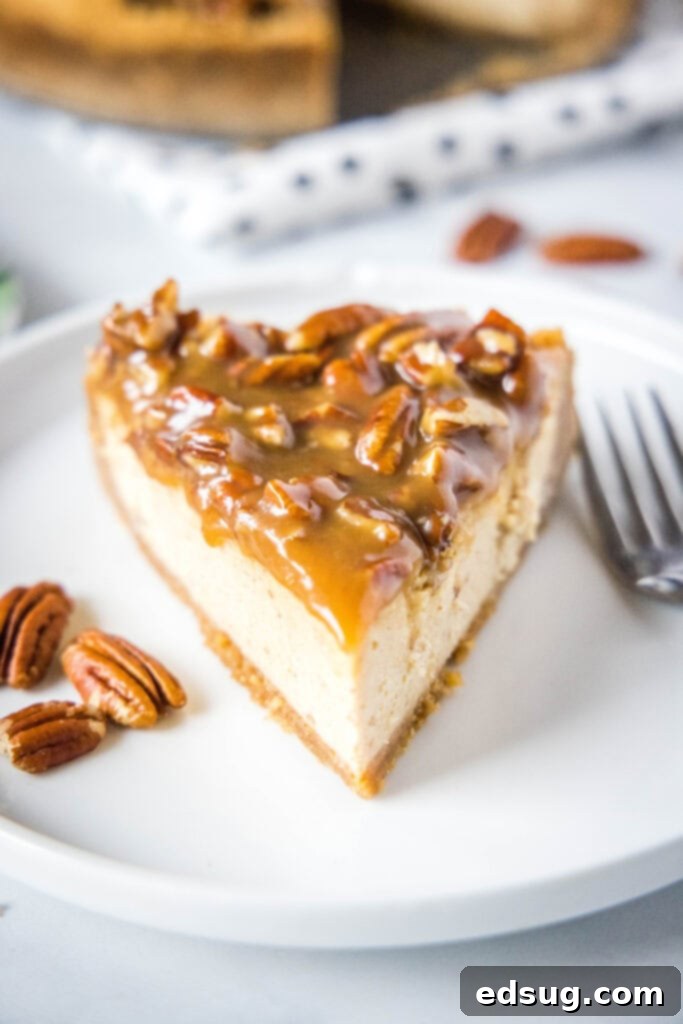A slice of Pecan Pie Cheesecake on a white plate with a fork, ready to be enjoyed.