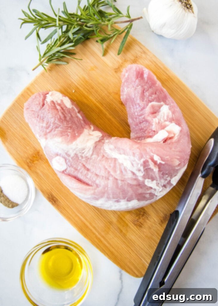 Ingredients for air fryer pork tenderloin including olive oil, rosemary, garlic, and seasonings on a white counter