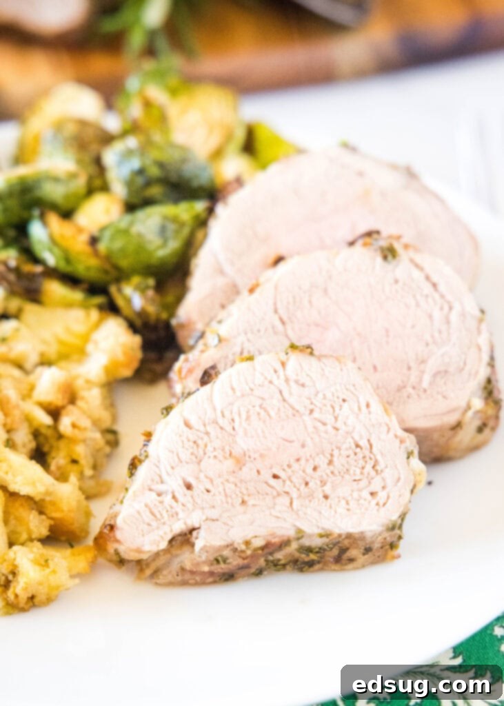 Air fried pork tenderloin slices served beautifully on a white plate with fresh herbs