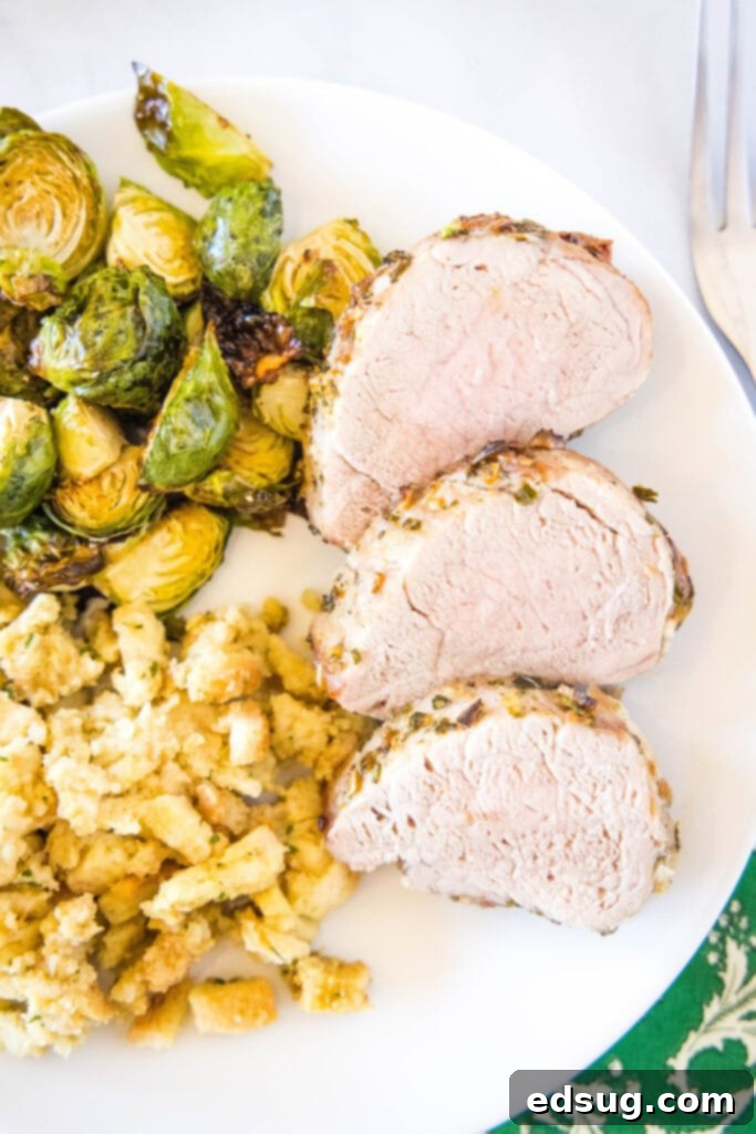 Three perfectly cooked slices of air fryer pork tenderloin presented on a white dinner plate