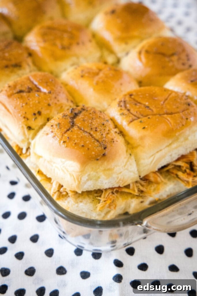 Baked buffalo chicken sliders in a glass baking dish, golden brown and bubbly, ready to be served