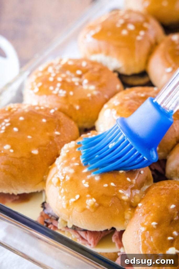 Brushing savory butter mixture onto French Dip sliders before baking.