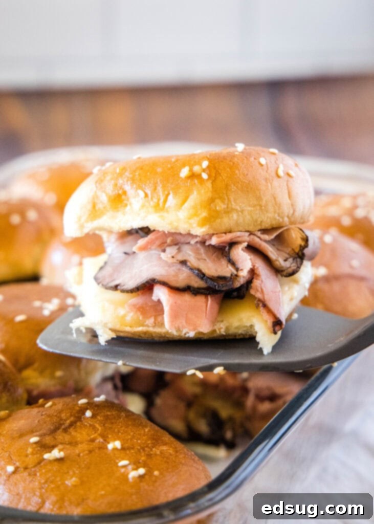 A French Dip slider being lifted with a spatula, showing melted cheese and roast beef.