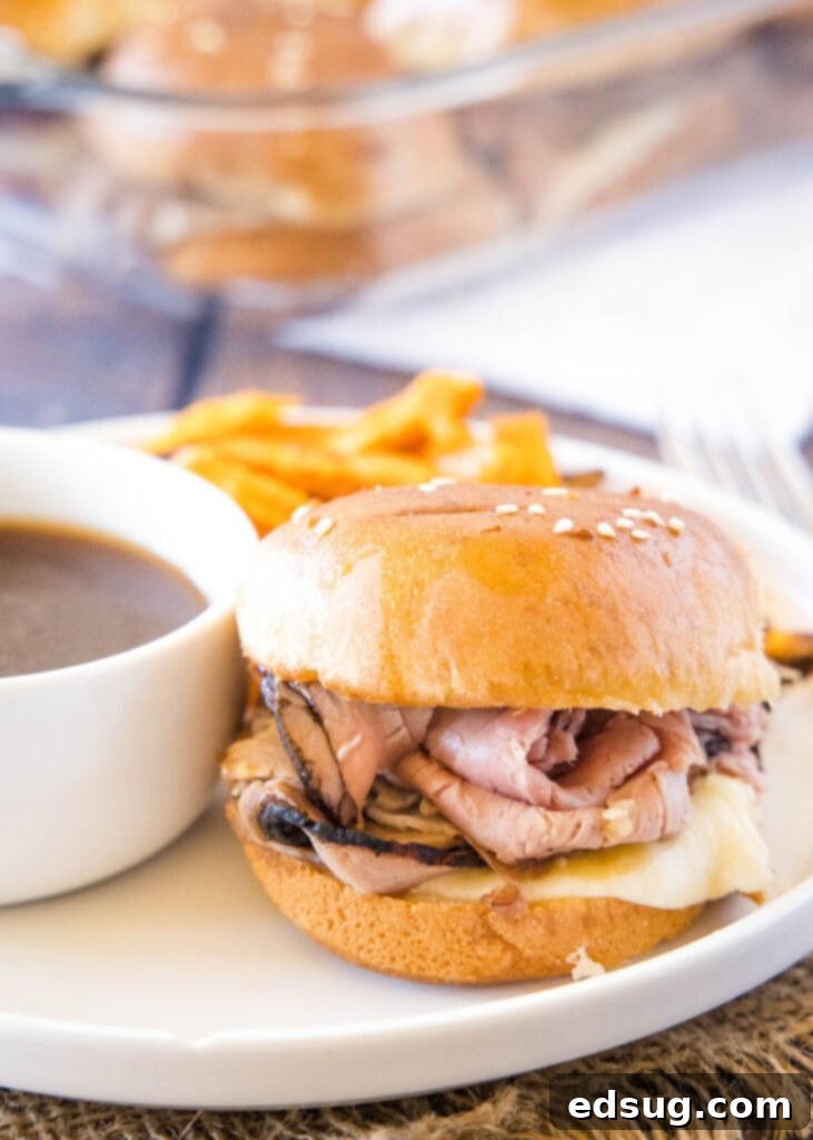 White plate with a French Dip slider and a small bowl of au jus for dipping.