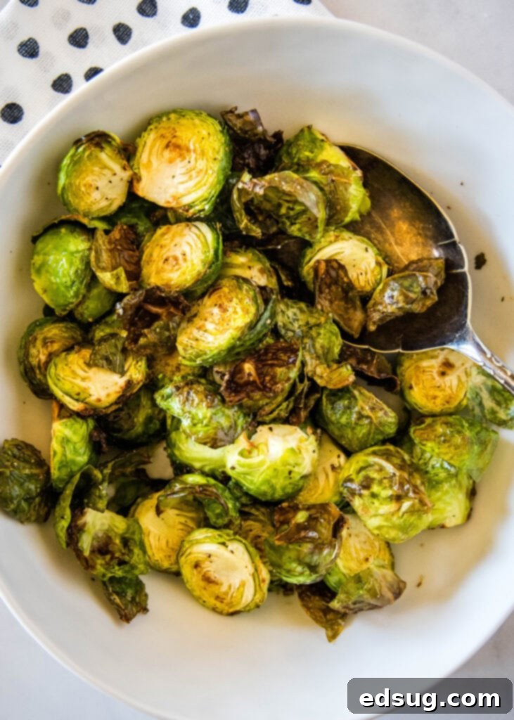Golden Crispy Air Fryer Brussels Sprouts 2 Looking down at air fryer Brussels sprouts in a white bowl, perfectly crispy and golden
