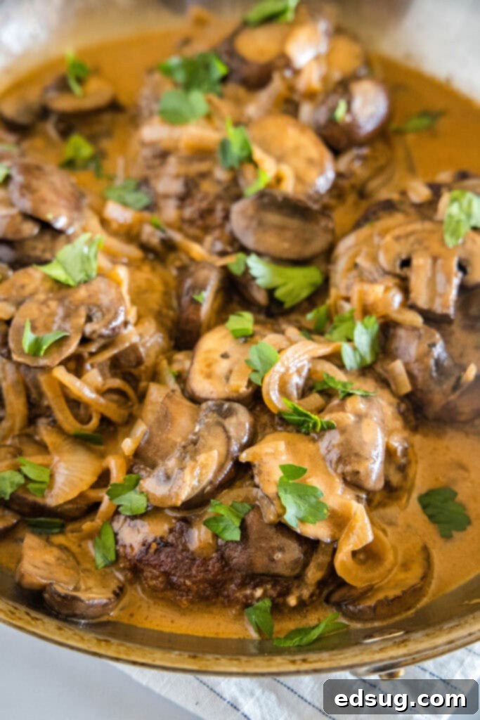 Bobby Flay Ultimate Salisbury Steak 2 Sizzling Salisbury steak patties drowning in creamy mushroom gravy in a large skillet