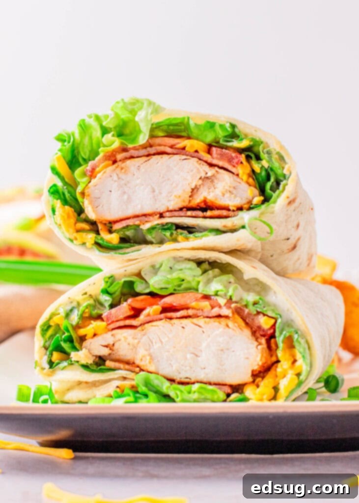 Signature Chicken Bacon Ranch Wrap 5 A tightly rolled chicken bacon ranch wrap, cut in half and presented on a white plate.