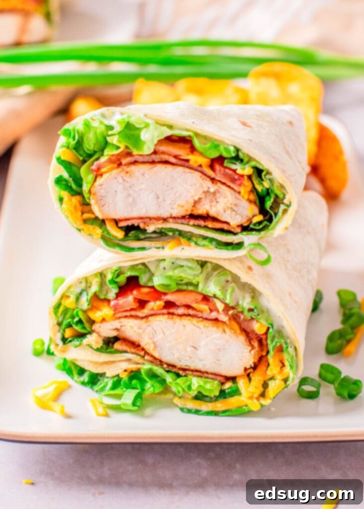 Signature Chicken Bacon Ranch Wrap 6 Overhead view of a chicken bacon ranch wrap cut in half on a white plate, ready to eat.