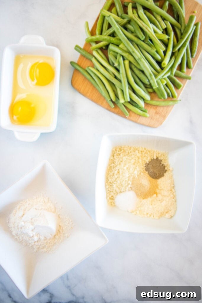 Ingredients laid out for making green bean fries, including fresh green beans, breadcrumbs, and cheese