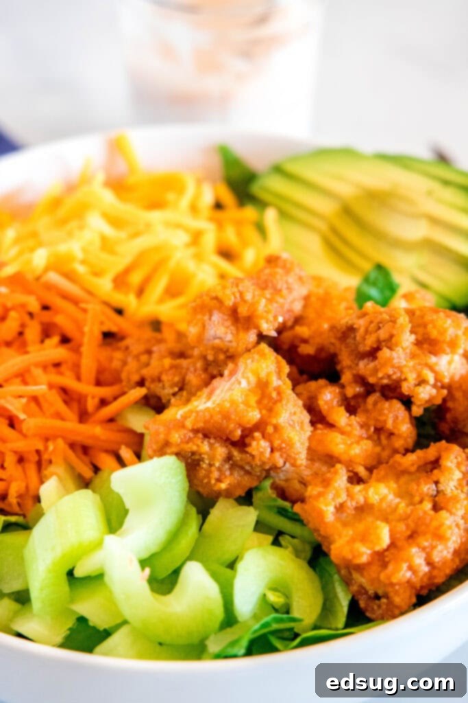 Kickin' Buffalo Chicken Salad 3 Close up view of crispy buffalo chicken tenders on a fresh salad bed.
