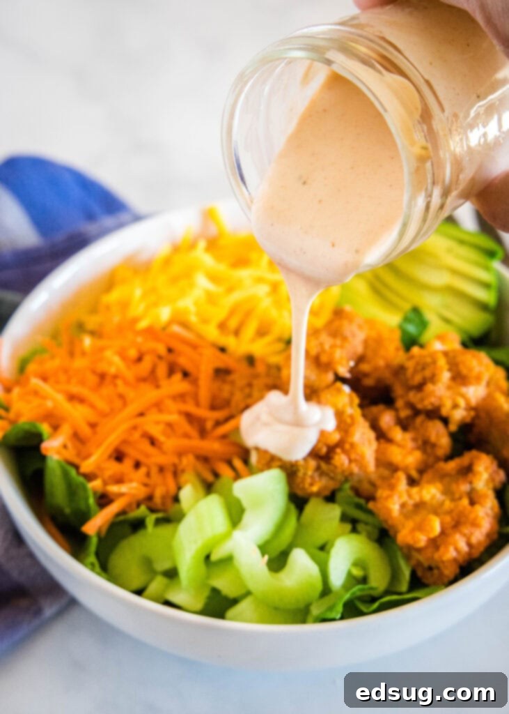 Kickin' Buffalo Chicken Salad 4 Pouring spicy ranch dressing over a bowl of buffalo chicken salad.
