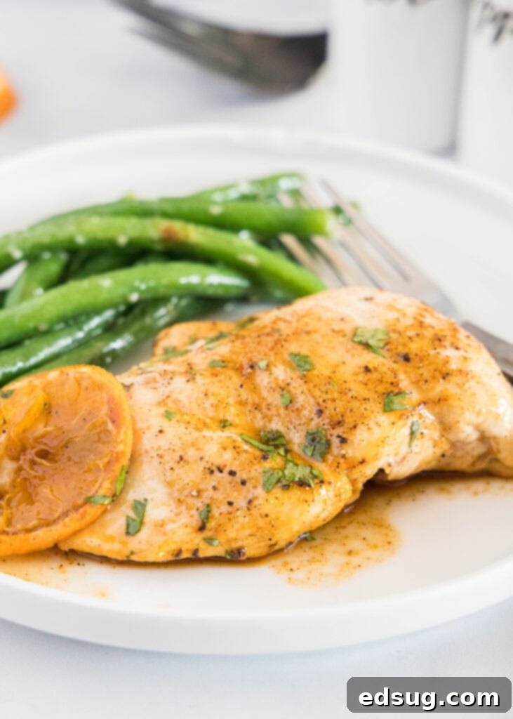 Sticky Orange Chicken 2 A white plate featuring perfectly cooked orange glazed chicken garnished with fresh green beans, highlighting the rich, glossy glaze.