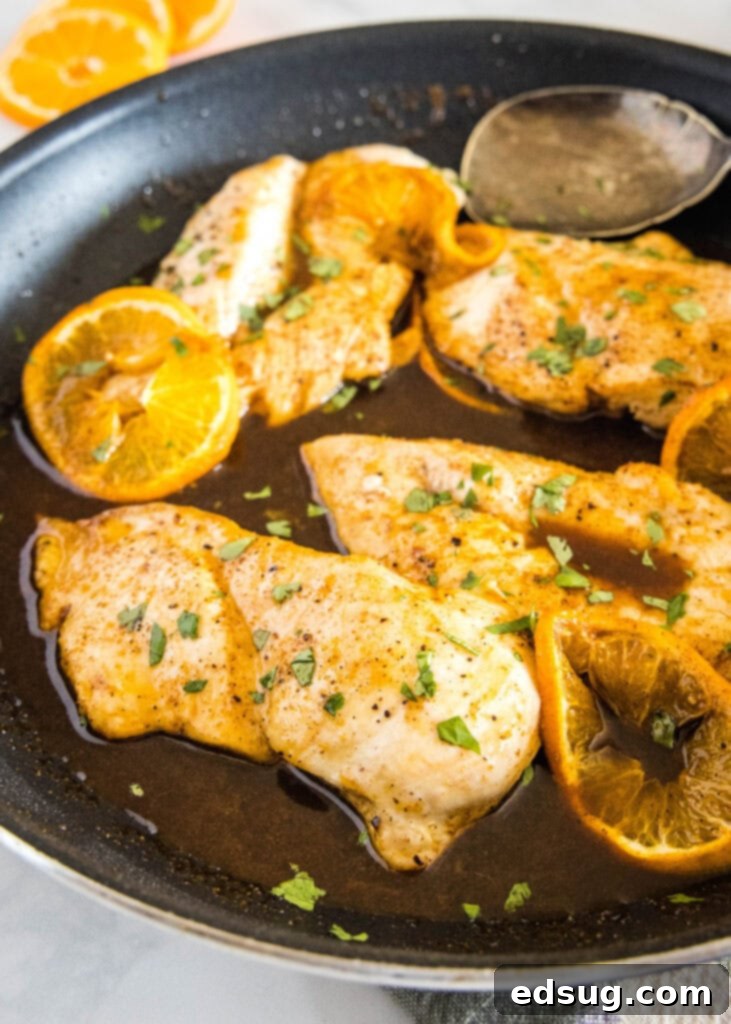 Sticky Orange Chicken 4 A close-up view of orange glazed chicken breasts simmering in a large skillet, surrounded by the rich, thick sauce.