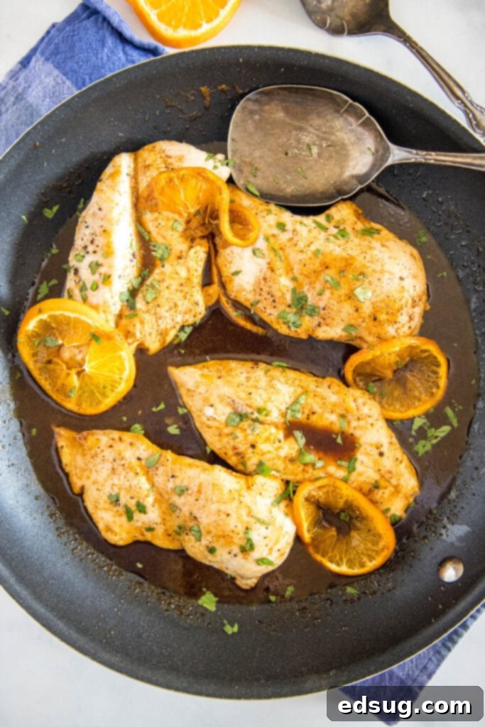 Sticky Orange Chicken 5 A large, rustic skillet filled with oven-baked orange glazed chicken, glistening with sauce and ready to be served.