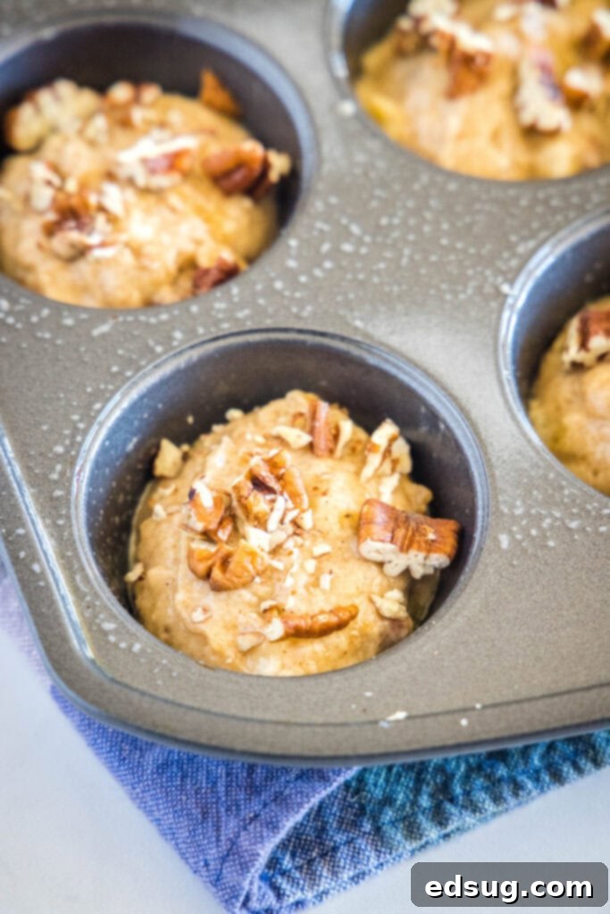 Perfect Banana Nut Muffins 4 banana muffins topped with nuts in muffin tin ready for the oven
