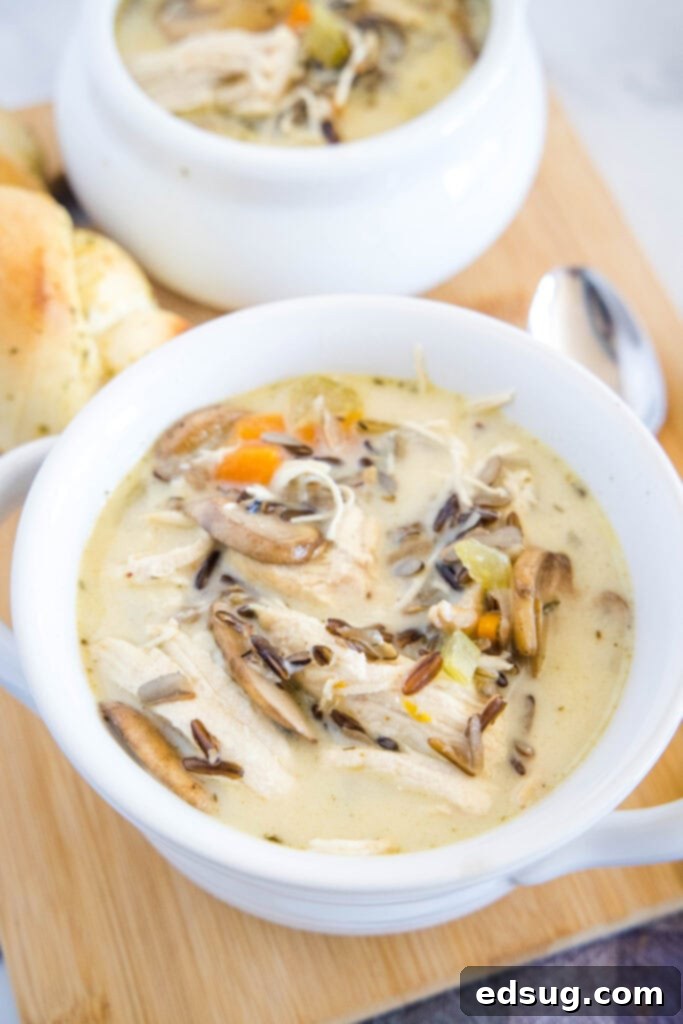 Hearty Instant Pot Chicken Wild Rice Soup 2 Two bowls of creamy Instant Pot Chicken Wild Rice Soup served on a wooden board, garnished with fresh herbs