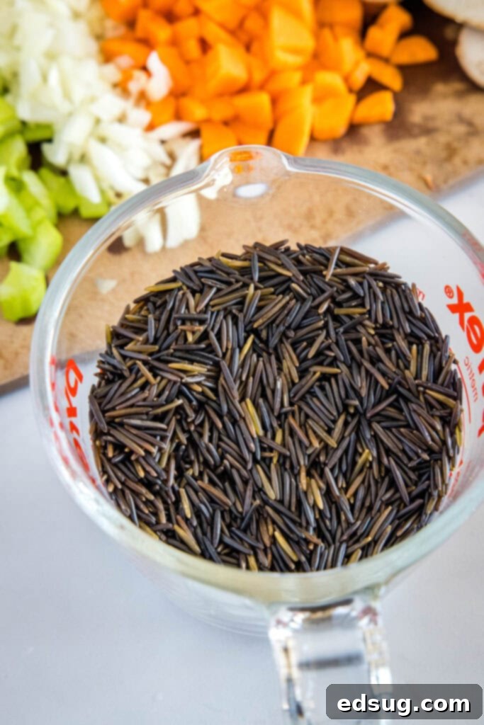 Hearty Instant Pot Chicken Wild Rice Soup 3 A measuring cup filled with uncooked wild rice, showcasing its distinct, elongated grains