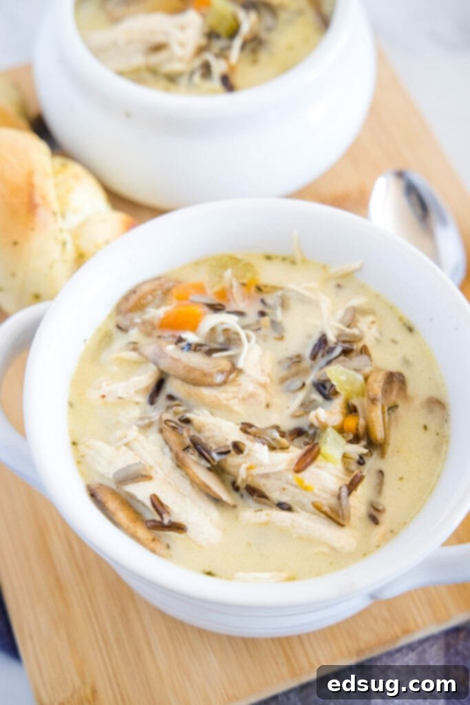 Hearty Instant Pot Chicken Wild Rice Soup 4 Three bowls of creamy Instant Pot Chicken Wild Rice Soup arranged on a wooden board