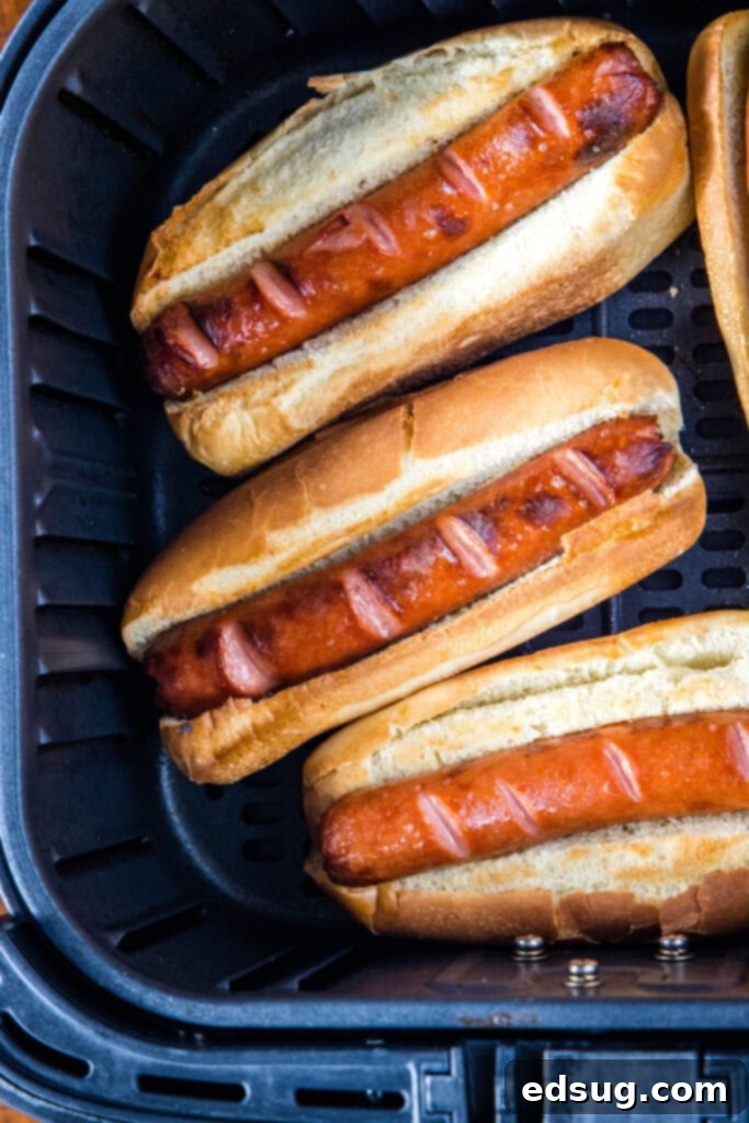 Perfect Air Fryer Hot Dogs 3 hot dogs in buns inside air fryer basket