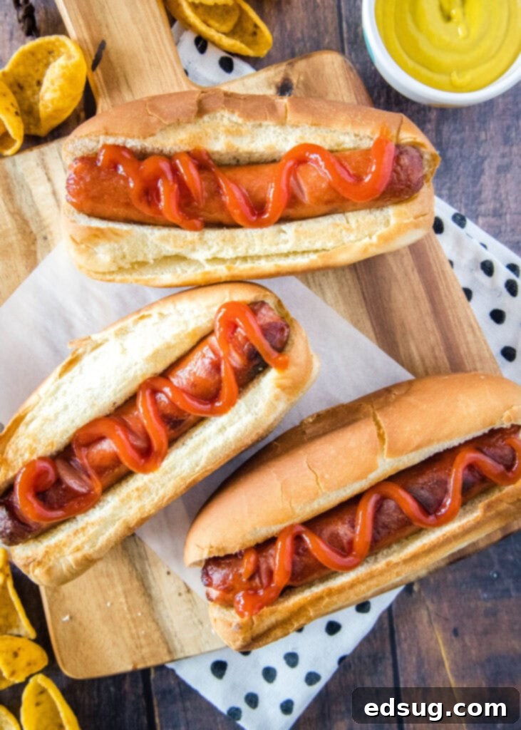 Perfect Air Fryer Hot Dogs 5 hot dogs topped with ketchup on a cutting board